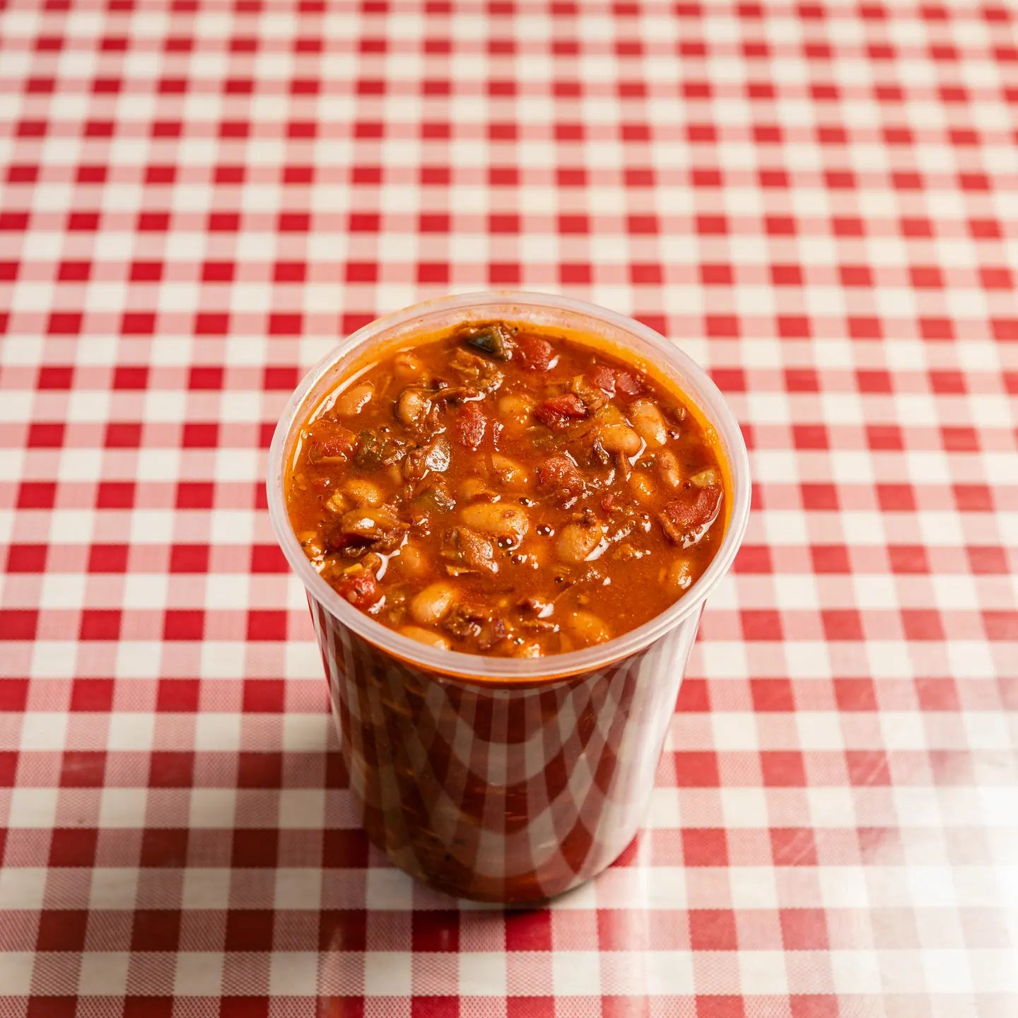 A cup of Goldee's brisket beans on a red gingham table