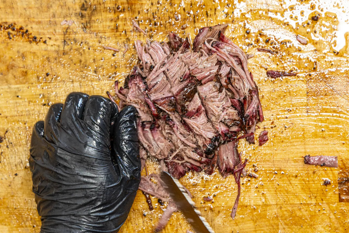 Chopped brisket gathered on the butcher block beside the knife