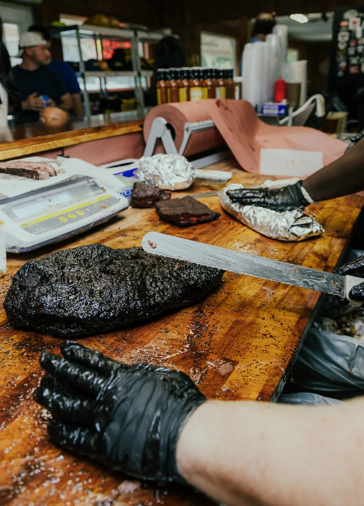 Slicing a brisket on the block beside the scale, ready for service