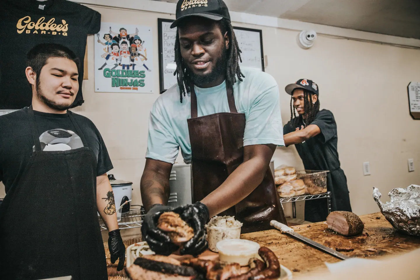 Three of the Goldee's crew working the counter, slicing brisket and building trays mid-service