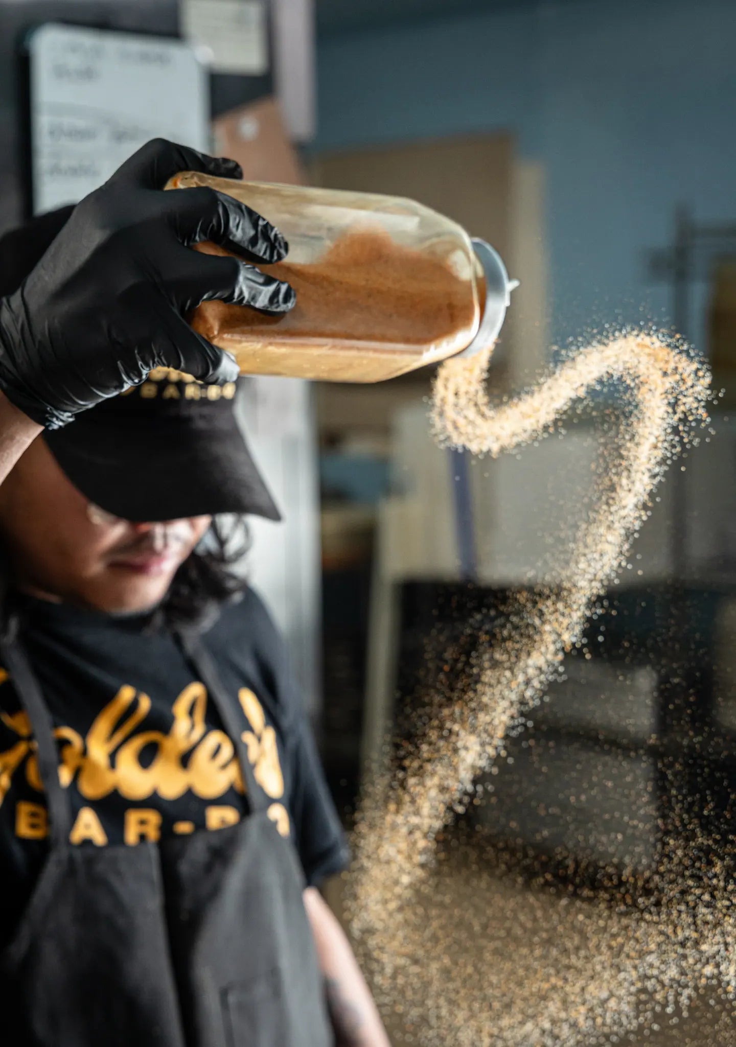 A pitmaster throwing an arc of rub across the room