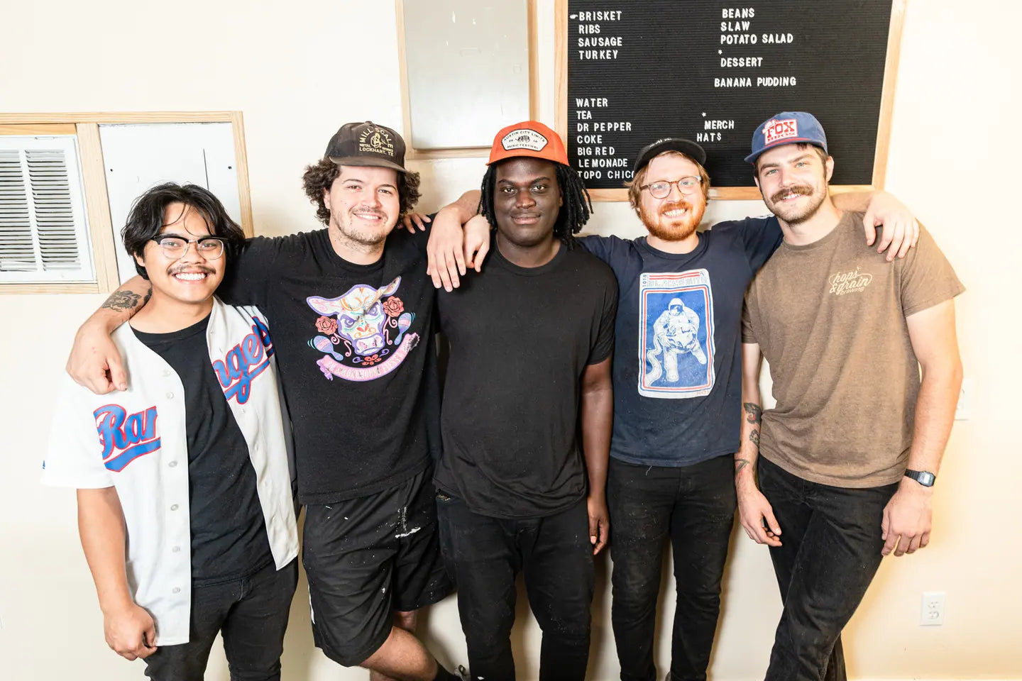 The five founders of Goldee's together in front of the menu board