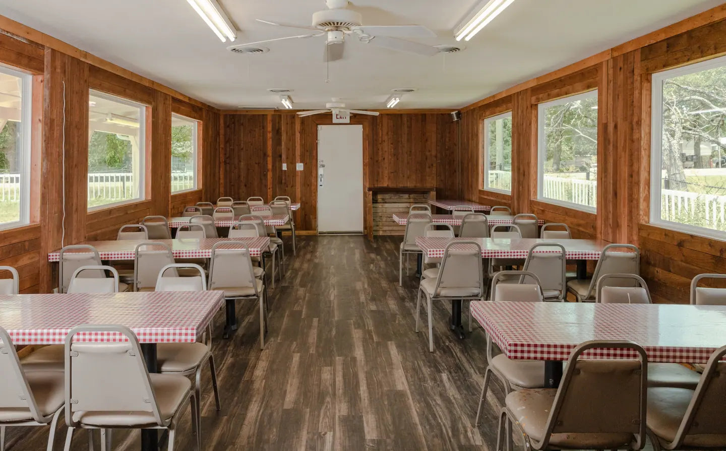 Goldee's dining room set with gingham cloths and metal chairs, empty and ready