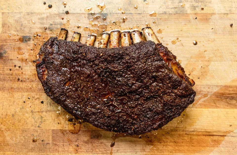 A whole rack of smoked lamb ribs on a wooden board